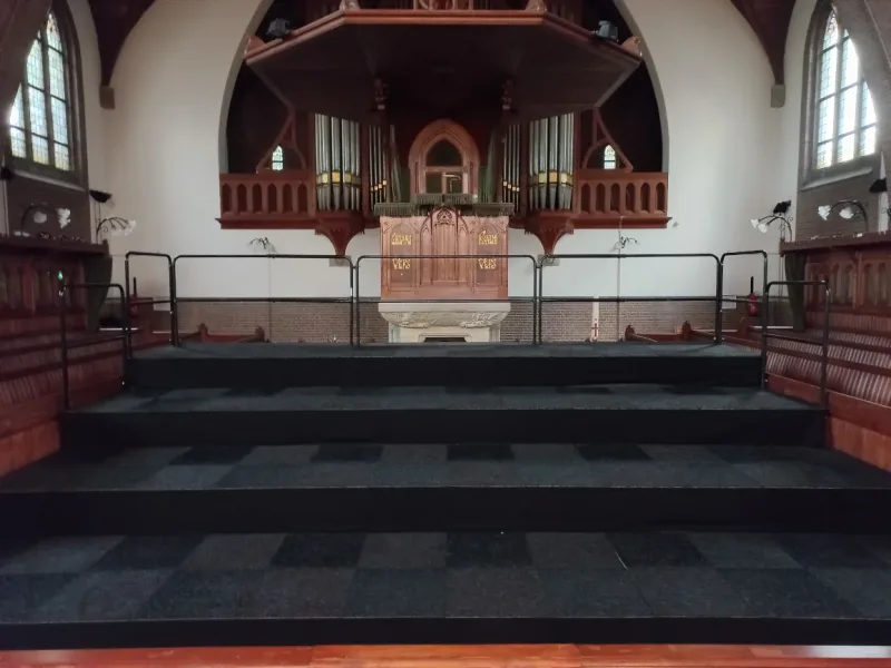 Tribune met vloertegels en zwarte rok in kerk